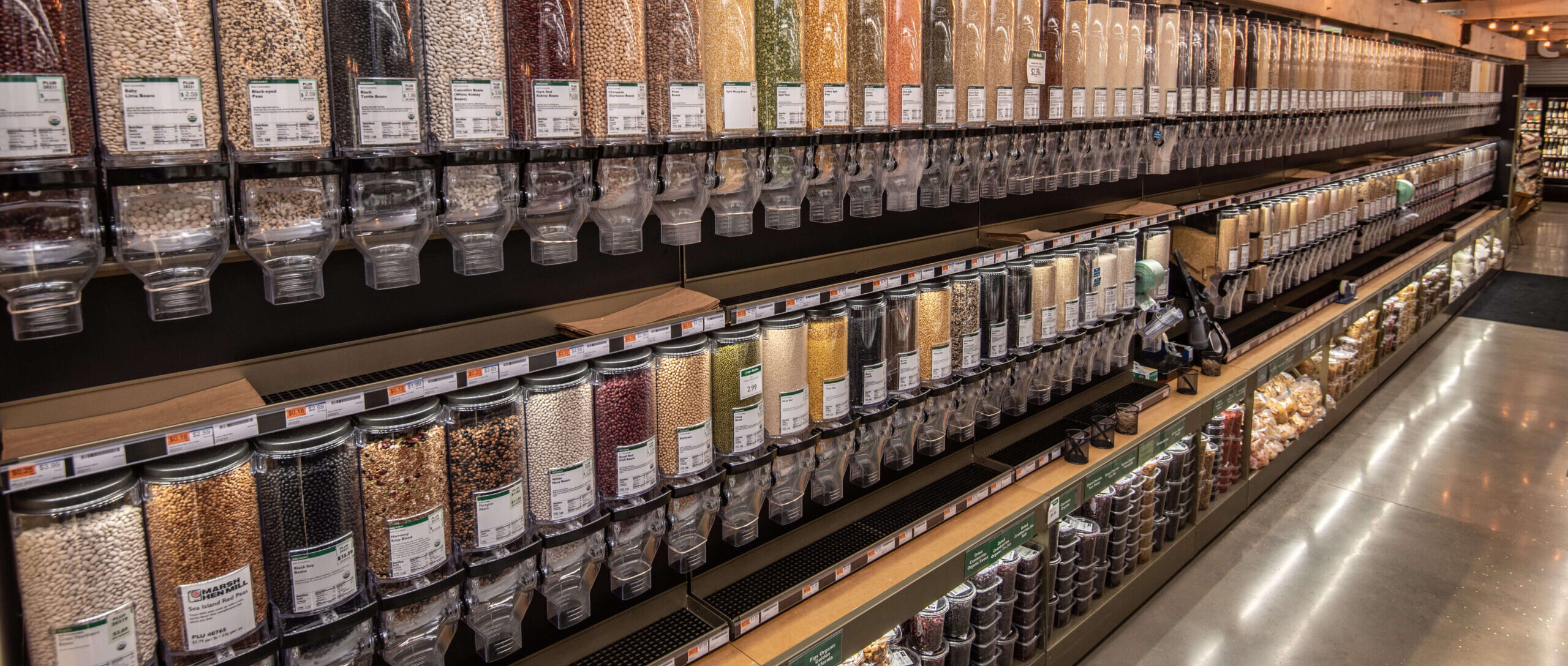 A photo of a store aisle with gravity bins lining the wall.