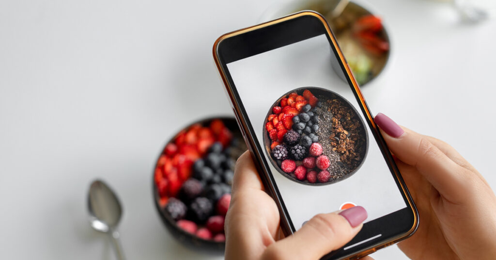 a photo of fresh fruit and granola being taken with a cell phone